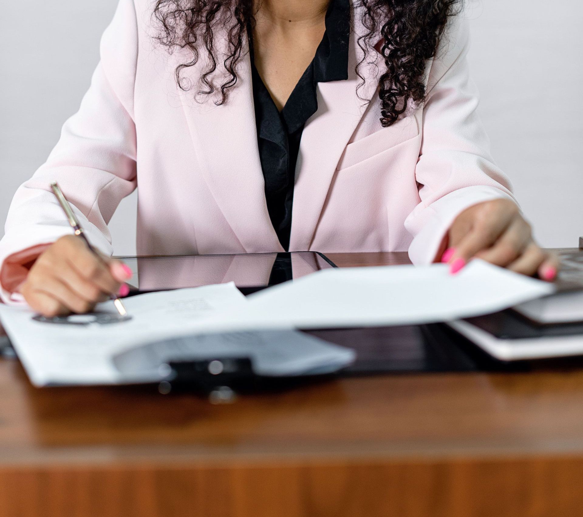 Focused businesswoman signing important documents at her office desk.
