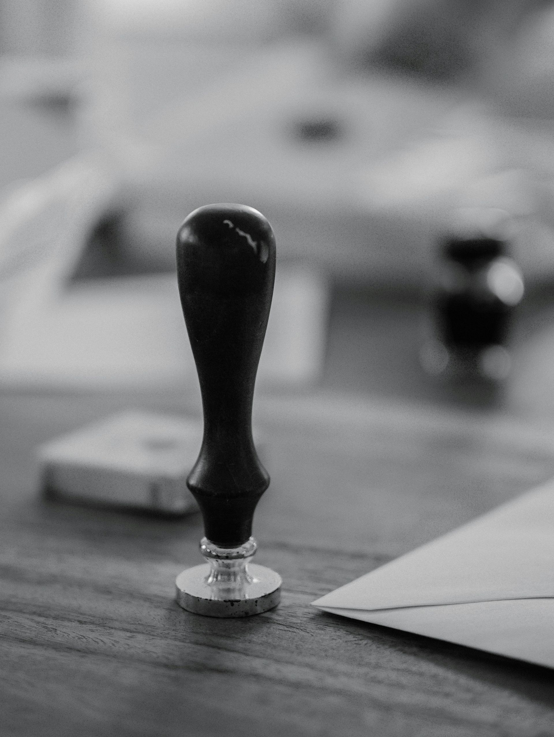 A wooden stamp sits on a wooden desk.